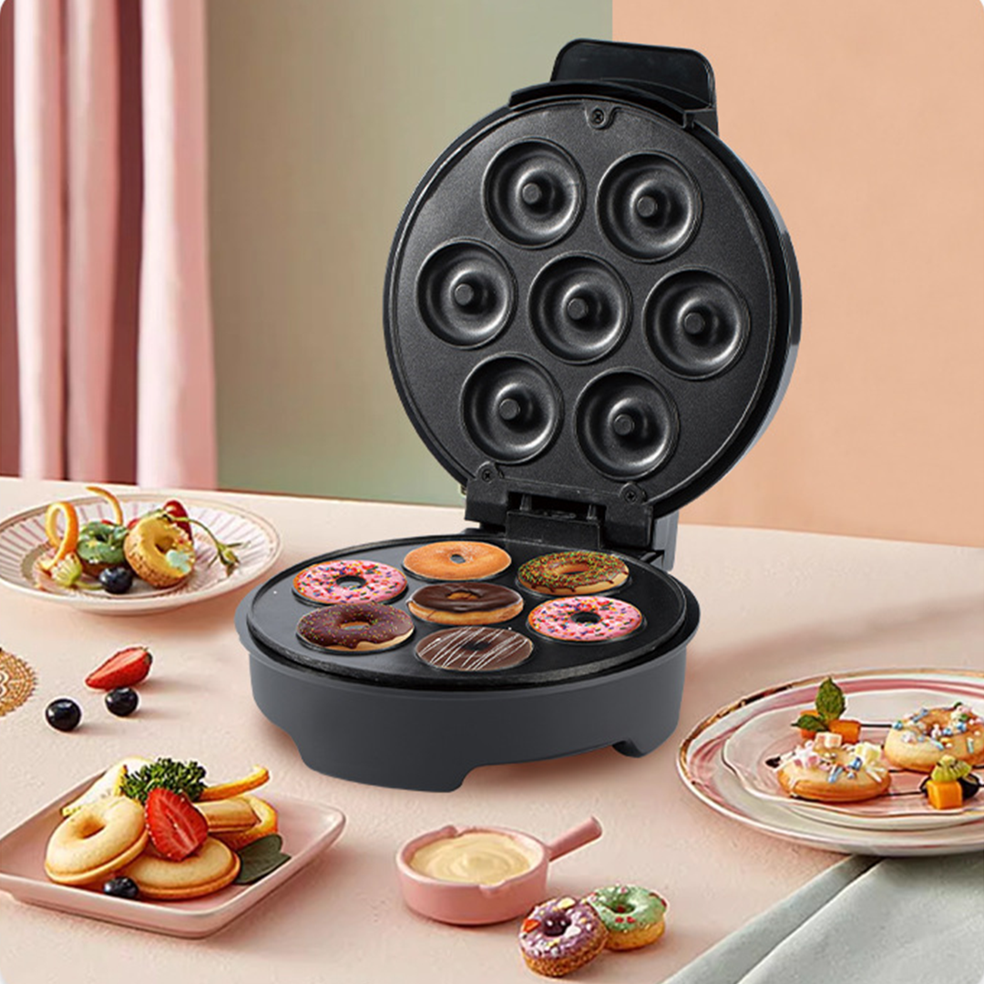 Donut maker with various donuts on a table with plates of donuts and fruit.