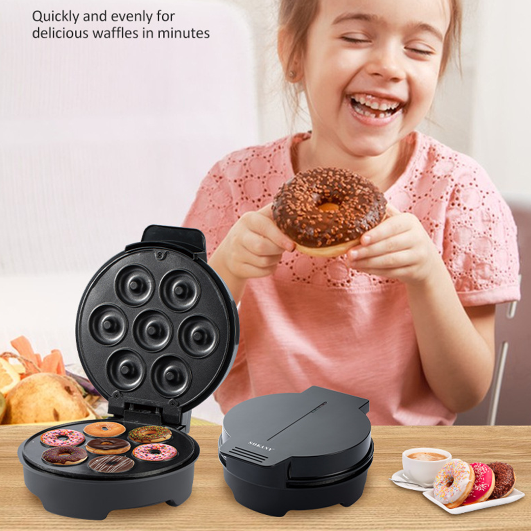 Child holding a waffle with a waffle maker on a table